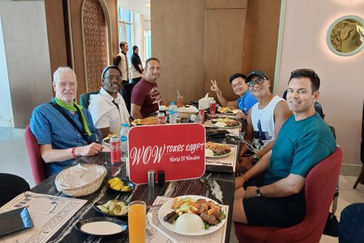 Travelers enjoying traditional Egyptian cuisine together at a local restaurant during a shared dining experience with WOW TOURS EGYPT.