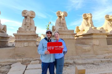 a lovely Couple visiting the Avenue of Sphinxes in Luxor holding WOW Tours Egypt sign