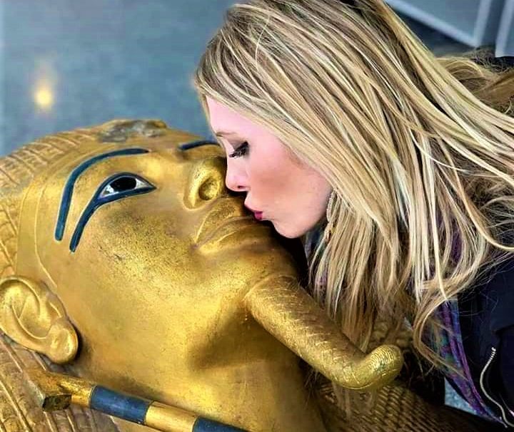 Woman posing with a golden pharaoh mask replica at the Egyptian Museum in Cairo