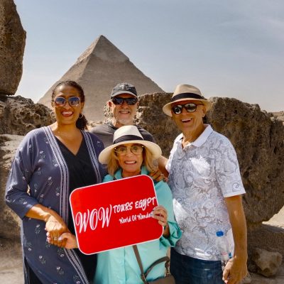 Group of guests holding WOW TOURS EGYPT sign in front of a pyramid at the Giza Plateau in Cairo.
