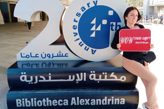 Guest posing beside the Bibliotheca Alexandrina anniversary monument in Alexandria.