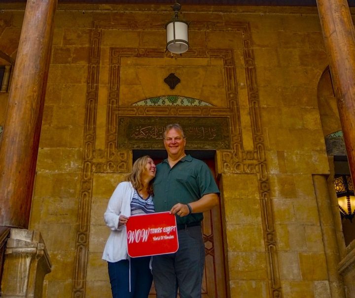 Couple holding WOW TOURS EGYPT sign at the entrance of the Hanging Church in Coptic Cairo, Cairo, Egypt