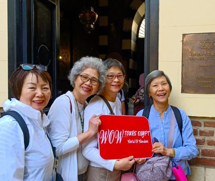 Group of female travelers holding WOW Tours Egypt sign at the entrance of Ben Ezra Synagogue in Coptic Cairo, Egypt