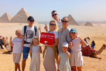 Happy family holding WOW Tours Egypt sign in front of the pyramids of Giza in Cairo Egypt