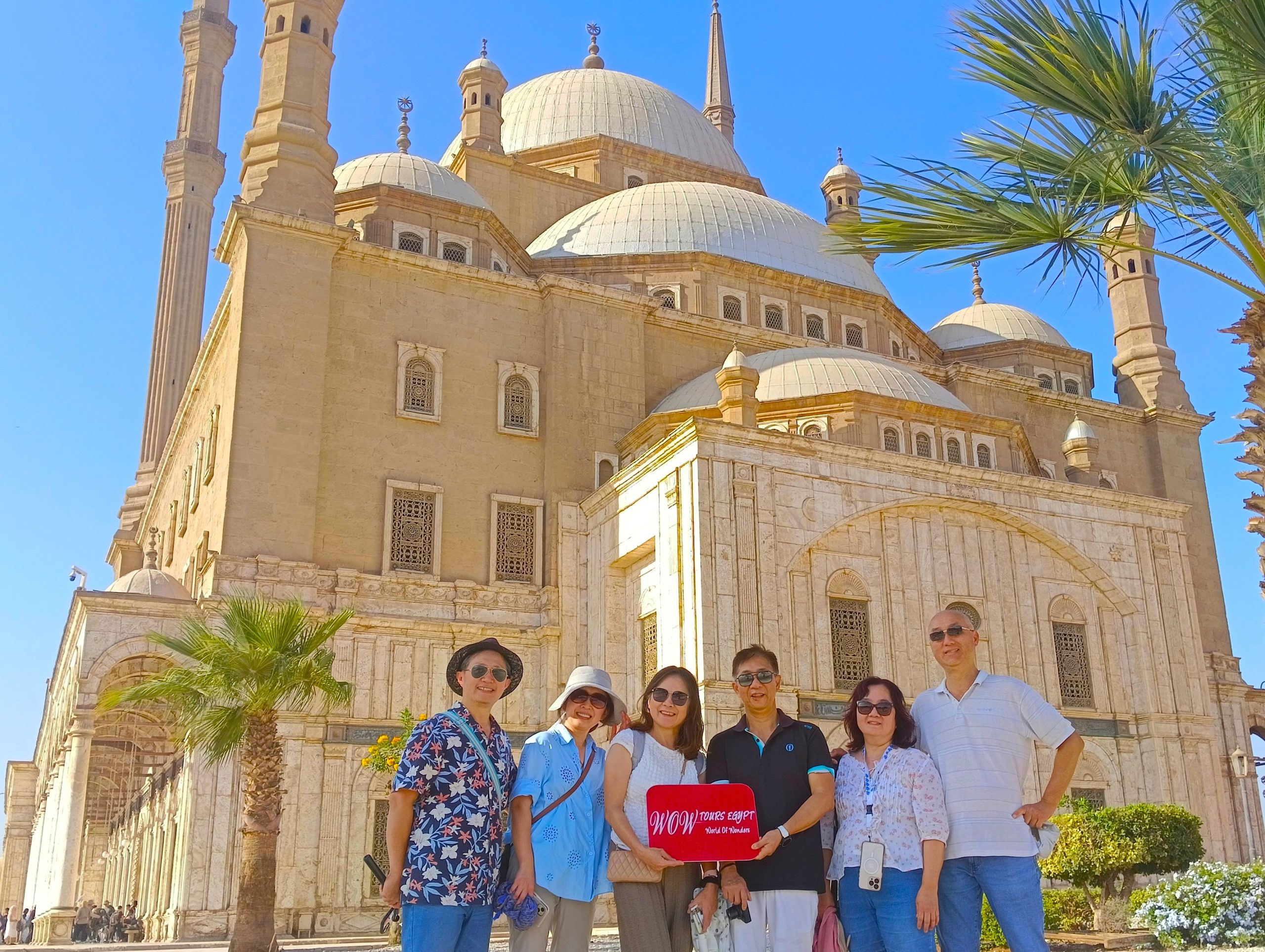 Travelers holding a WOW TOURS EGYPT sign in front of Mohamed Ali Mosque at the Citadel of Cairo, Egypt.