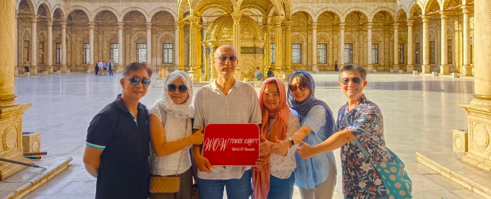 Travelers holding a WOW TOURS EGYPT sign in the courtyard of Mohamed Ali Mosque at the Citadel of Cairo, Egypt.