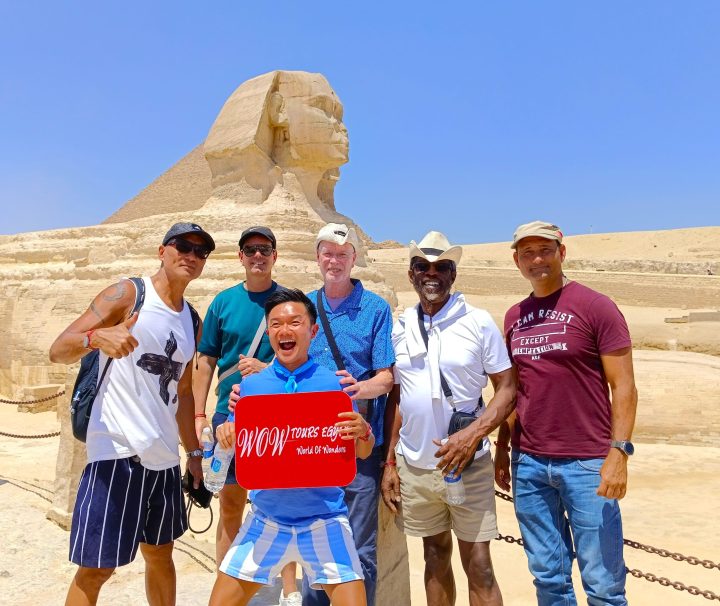 Group of travelers holding WOW Tours Egypt sign in front of the Great Sphinx of Giza Cairo Egypt.