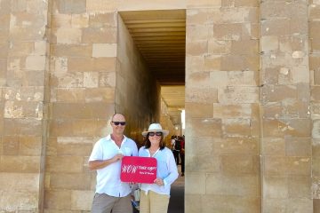 Couple standing at the doorway of the Step Pyramid complex in Saqqara Egypt holding WOW TOURS EGYPT sign